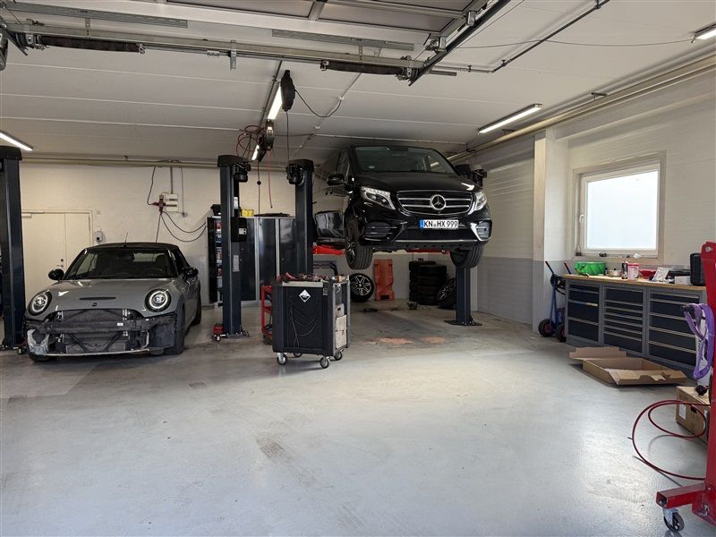 En bilværksted med to biler, en Mini Cooper og en Mercedes-Benz, samt værktøjskufferter og højtløfter