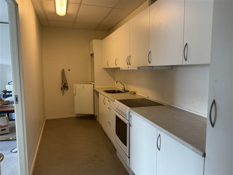 Et rent og moderne køkken med hvide skabe, lysegule vægge og en hvid gaskomfur med ovn