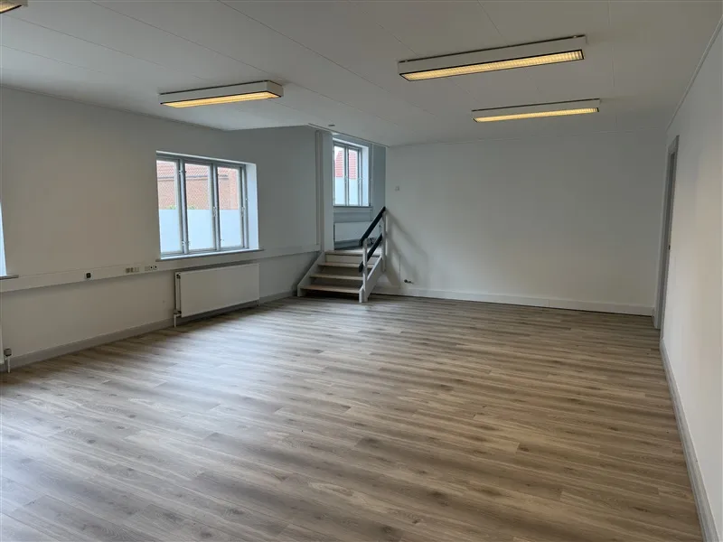 Kontorejendom med moderne indretning og lyse gulve, vinduer, trappe og radiatorer på væggen