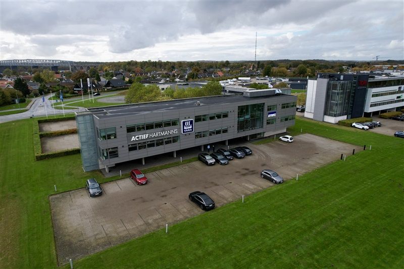 et kontorlejemål med Actief Hartinmanns logo på facaden og flere biler parkeret i forgrunden