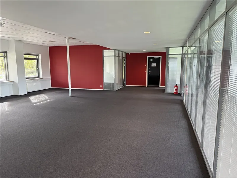 En tomt kontor med røde vægge og glasruder, gulvbelægning og to brandhøjre placeret mod væggen