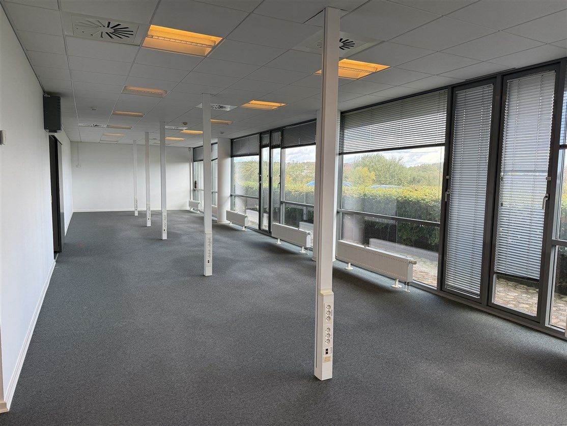 Lokale med højt til loftet, hvide vægge og gulv, store vinduer med jalousier, radiatorer, højt kvalitetsloft med