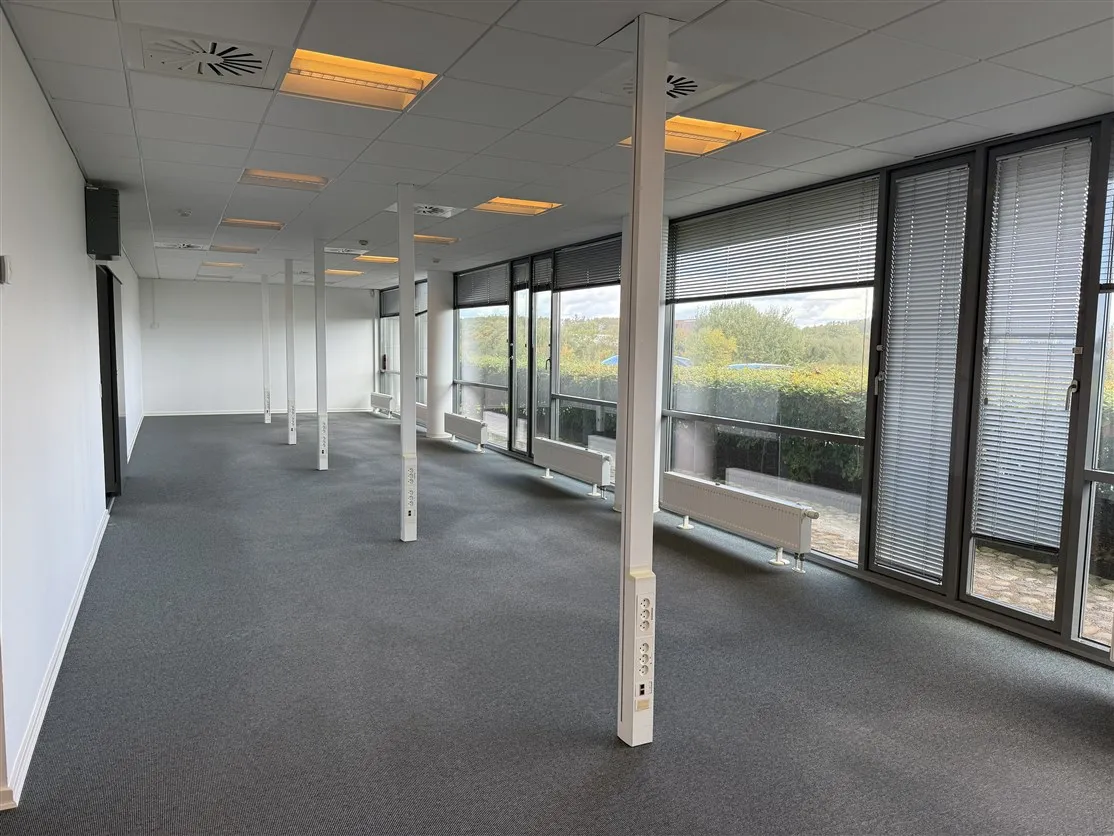 Lokale med højt til loftet, hvide vægge og gulv, store vinduer med jalousier, radiatorer, højt kvalitetsloft med