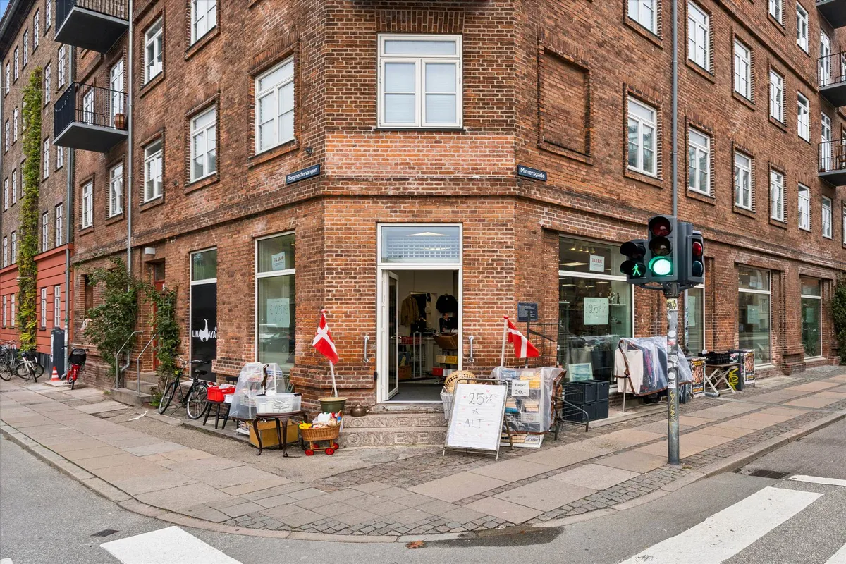 Hjørnebutik med skilte, røde faner og salgsskilt med 25 % rabat på alt