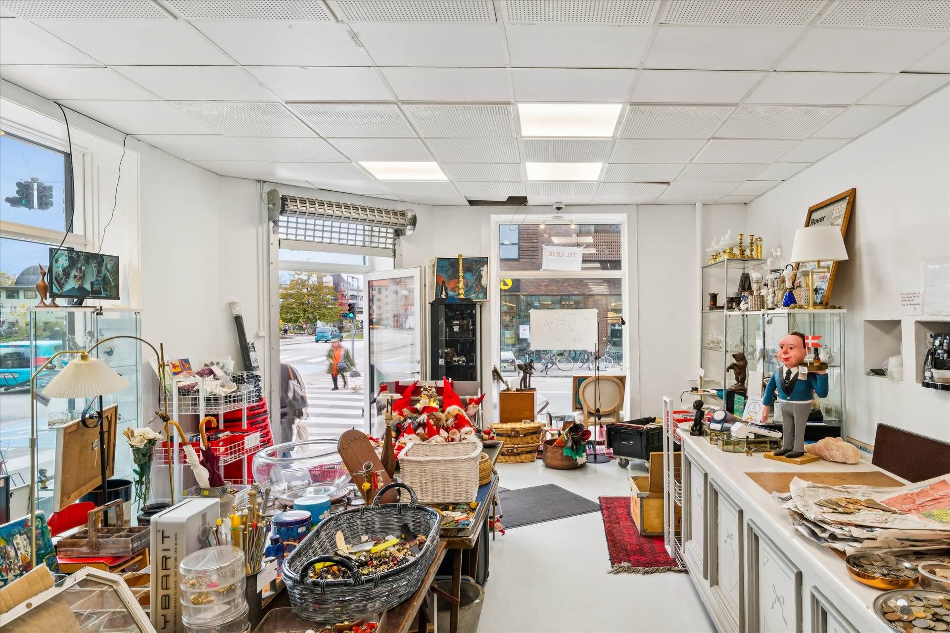 En stor antikvitetsbutik med mange genstande og kunstværker. Et gulv med en rødt tæppe og en hvid stol. Et kammer med flere