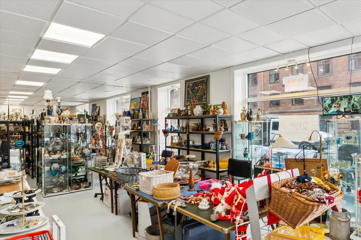 En hjørnebutik med mange hylder og udstillingsglasskabe fyldt med genstande og kuriositeter og et stort glasvindue med
