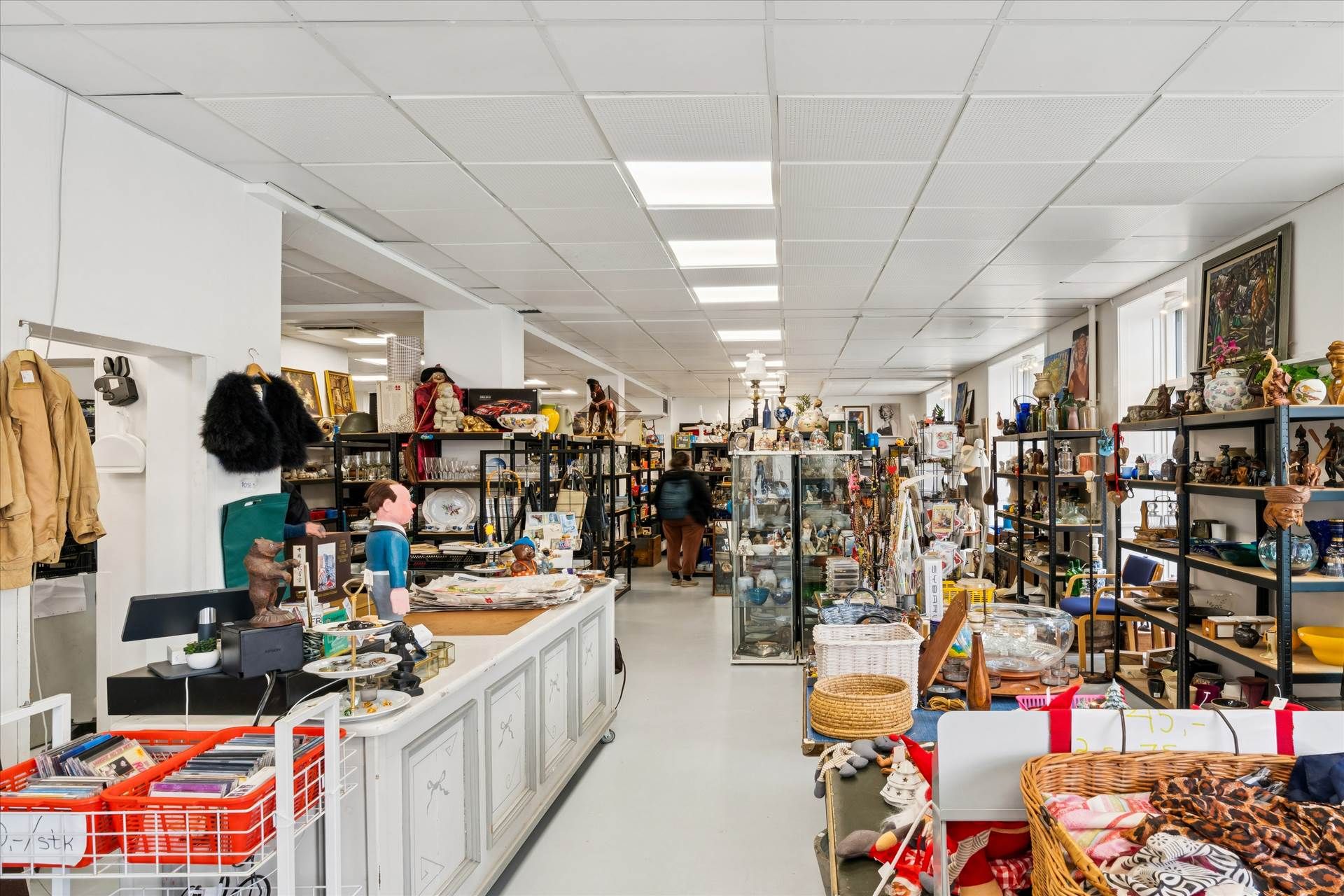 En hjørnebutik med håndværk og antikviteter og flere hylder med ting i glas og keramik