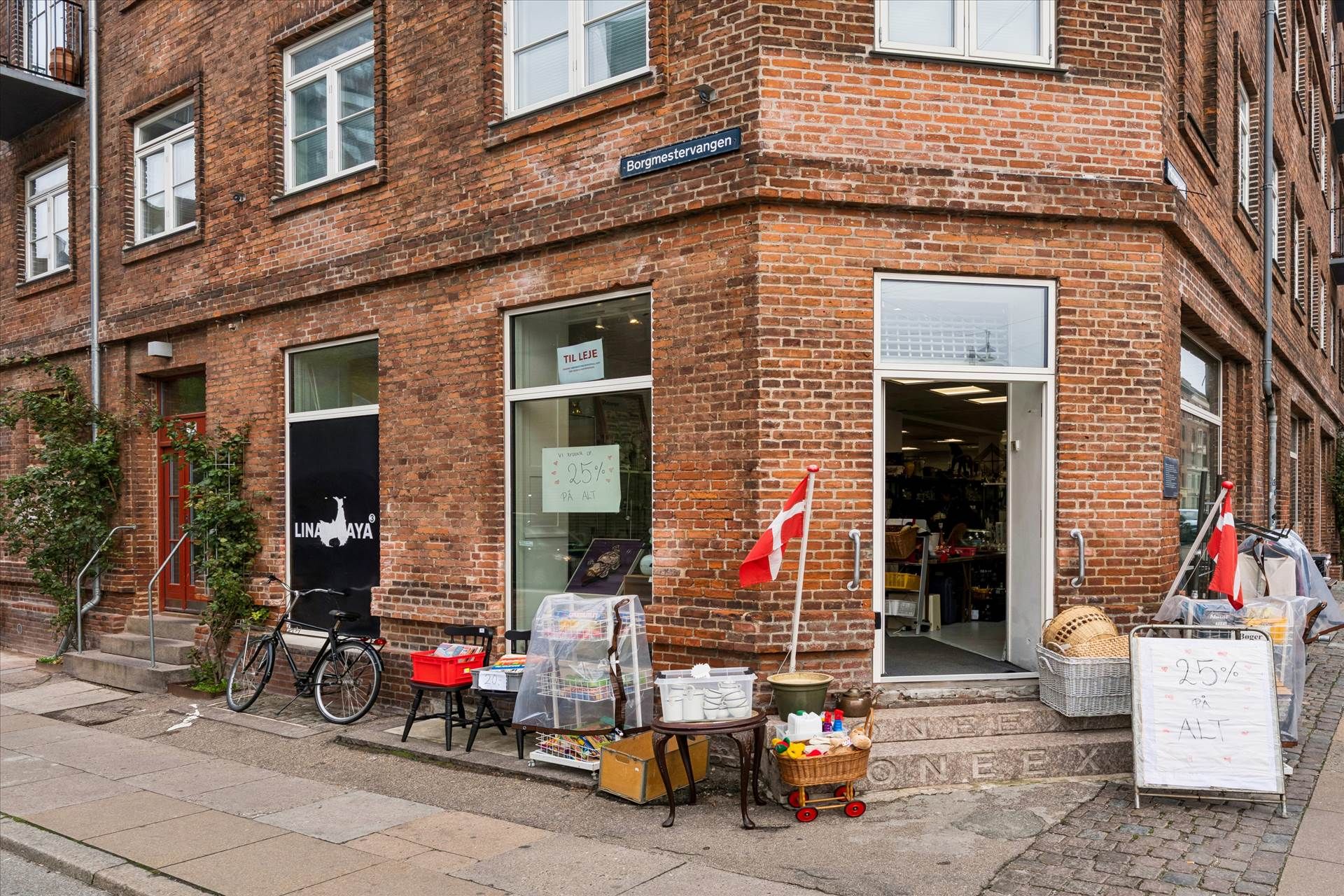 En hjørnebutik med navnet Lina YAYA, hvor der er en cykel og en rabatskilt med teksten 25% på alt.