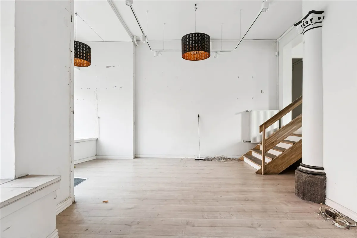 Lyst og indbydende erhvervslejemål med lyse lofter og højde, trætrapper og hvide vægge, dekoreret med lysekroner og trægulve