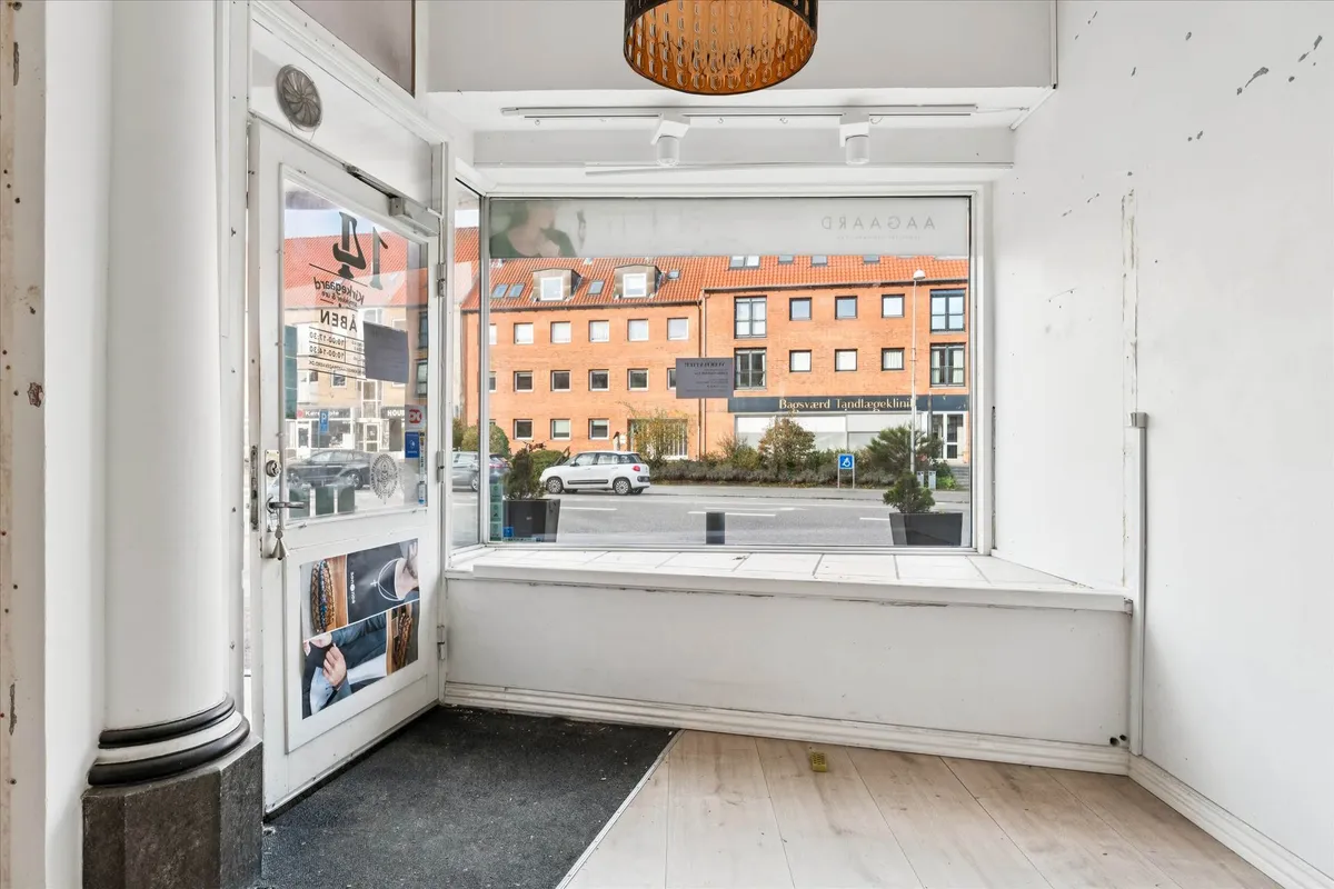 Indvendigt forretningslokal med højt loft og glasdøre, der vender ud mod Bagsværd Tandlægeklinik. Højt trafikområde med