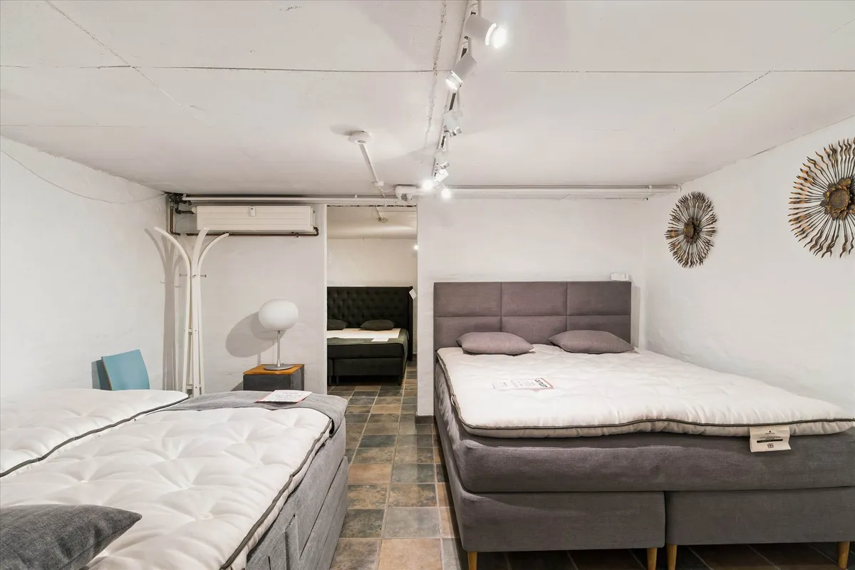 Et showroom med to nye sengebøffer og to ekstra sengebøffer med togæsser og hovedpuder i den bageste del af showroommet