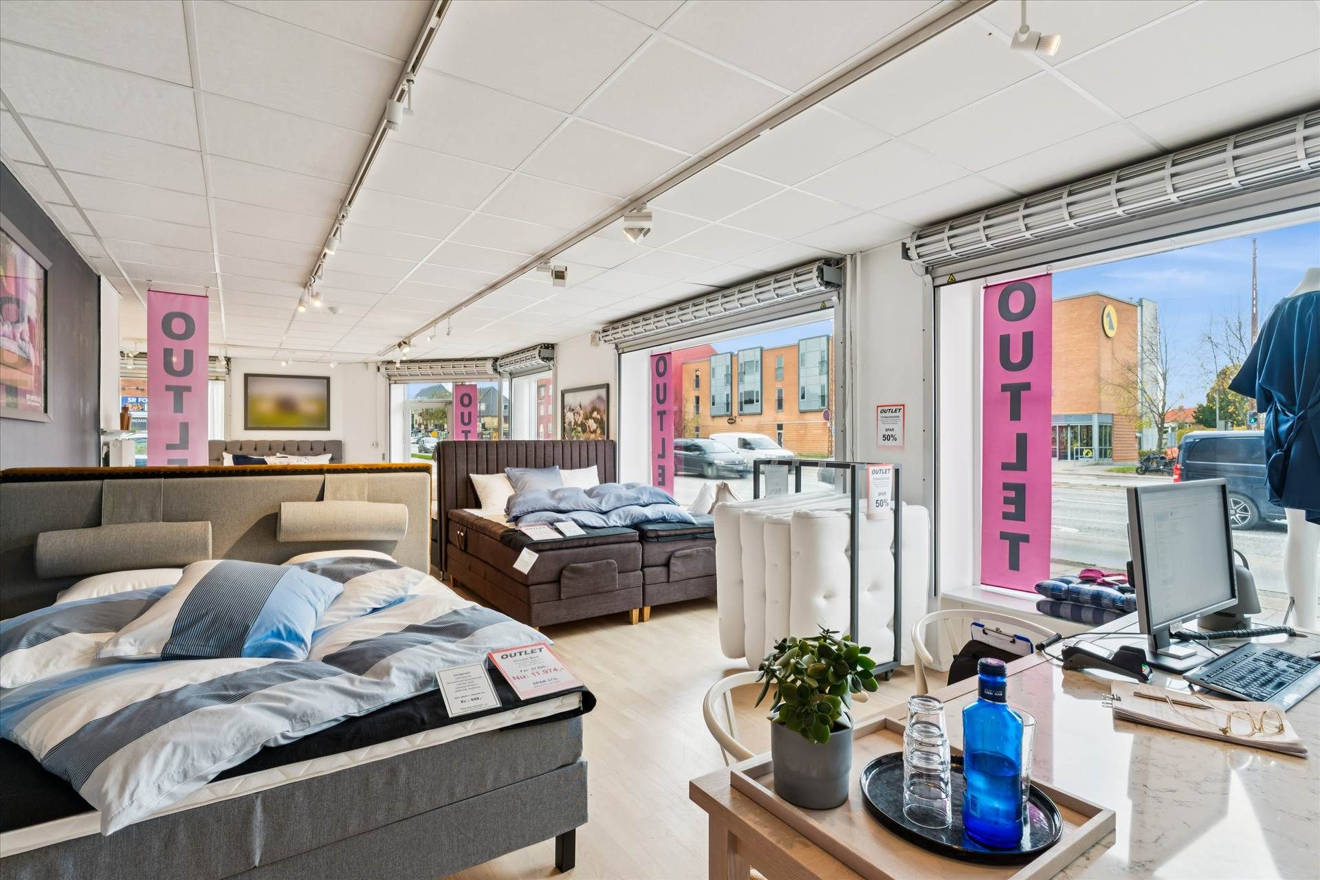 Erhvervslejemål med udsigt mod Roskildevej, indeholder senge og møbler, samt en kontorblok med computer og skrivebord