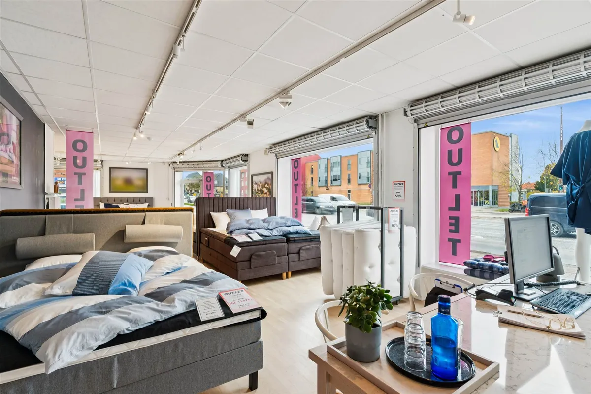 Erhvervslejemål med udsigt mod Roskildevej, indeholder senge og møbler, samt en kontorblok med computer og skrivebord