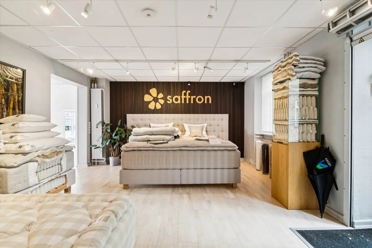 Inde i et Saffron møbelforretningslokal med sengetøj, tæpper og en plante i et hjørne