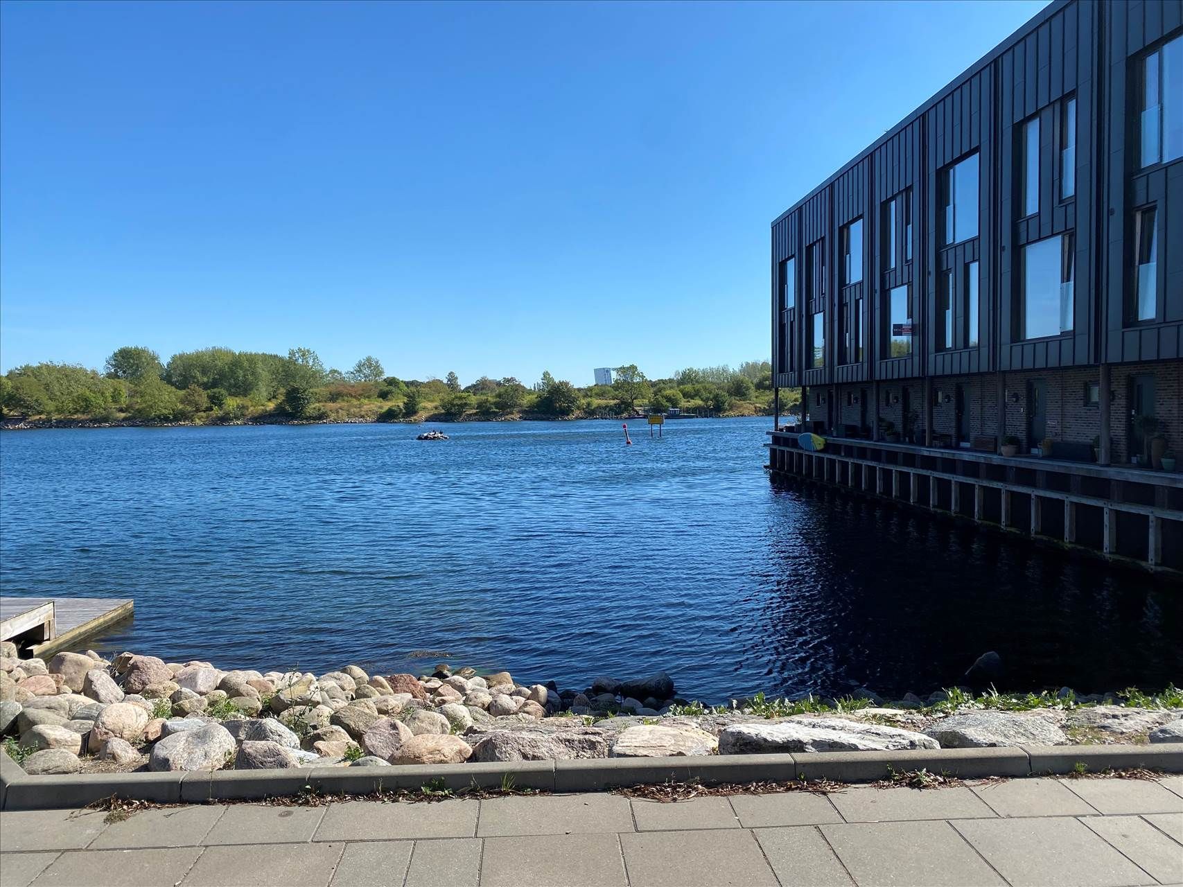 Store sten langs kajen med et hav og en stor bygning i baggrunden