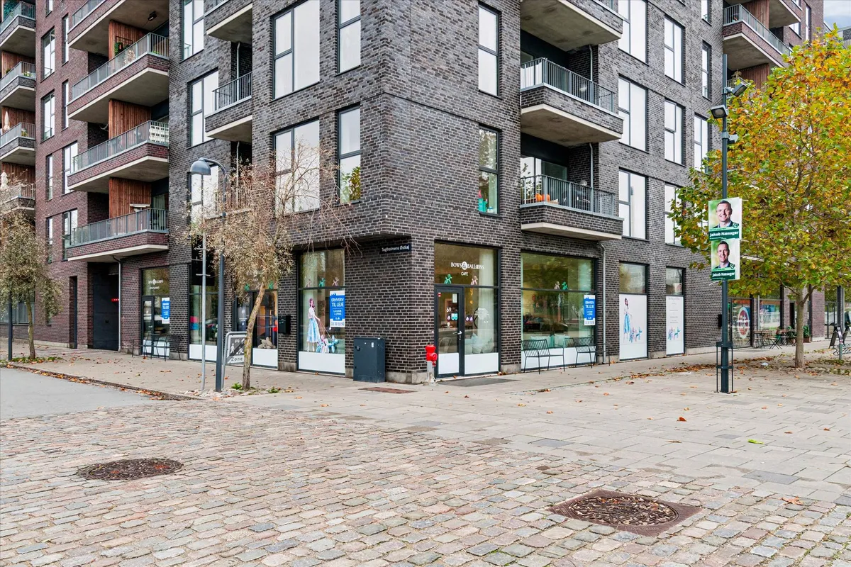 Moderne bygning med butikker og højtravmælere i østlig del af byen. Butikkerne har mange vinduer og terrasser. Allerede er