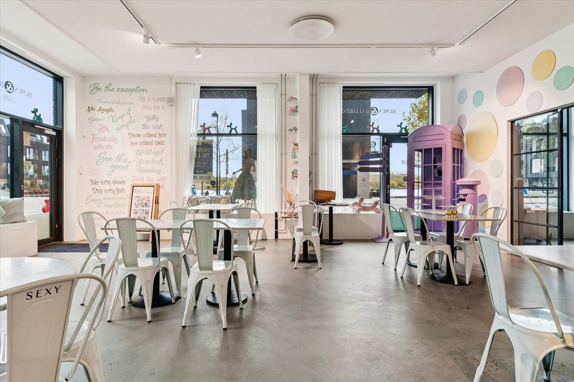 Moderne lokale med store ruder, lyse farver og hyggeligt møbelsæt med hvide stole og borde