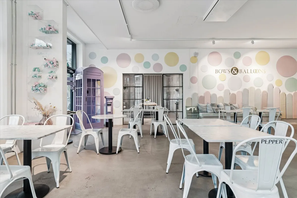 Restaurant med hvide stole og runde vægpaneler med forskellige farver og mønstre. Der er flere runde og firkantede borde med