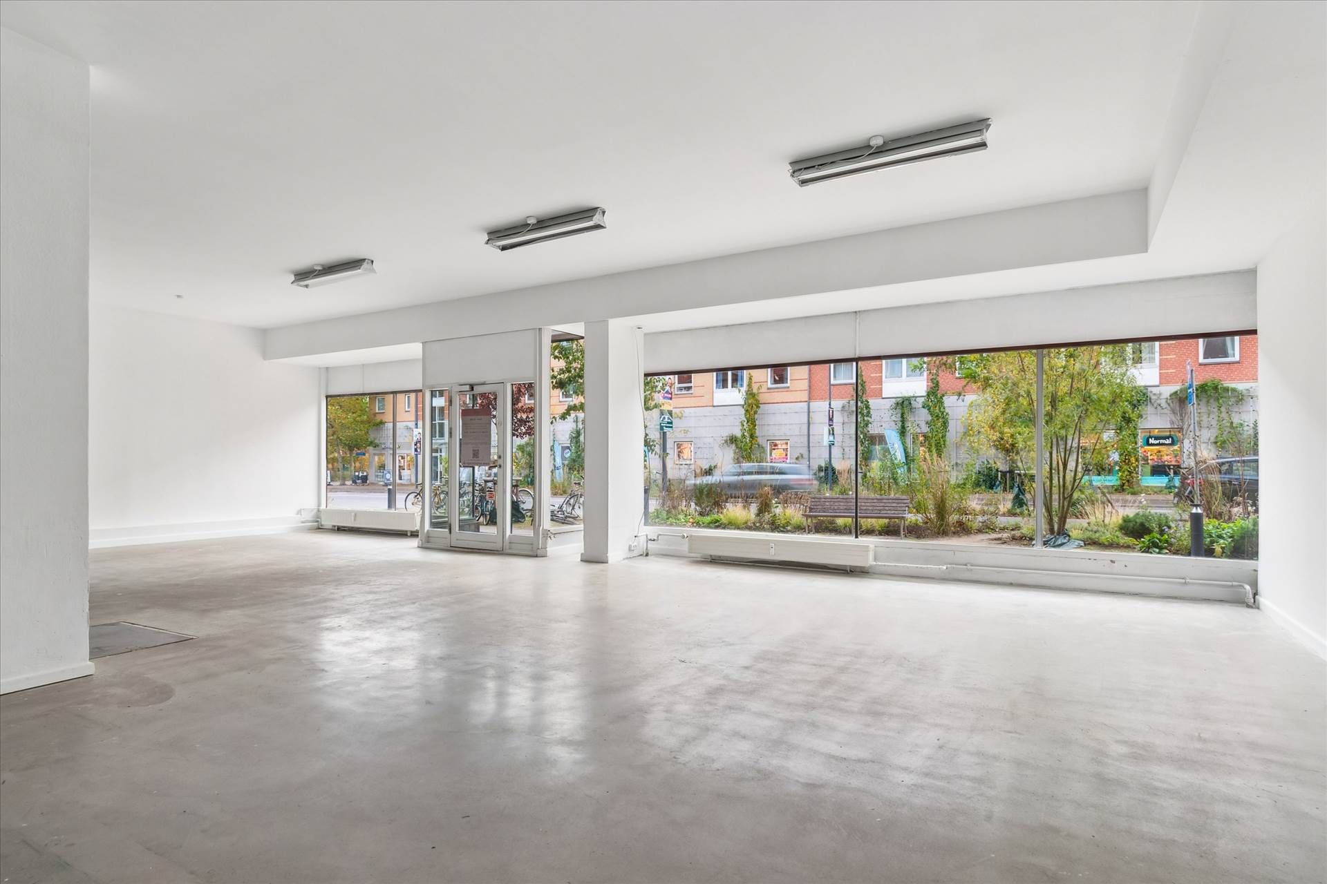 Velindrettet og ren butik med højt til loftet, lyse vinduer og møbler, gulv og vægge i hvidt og lysegråt