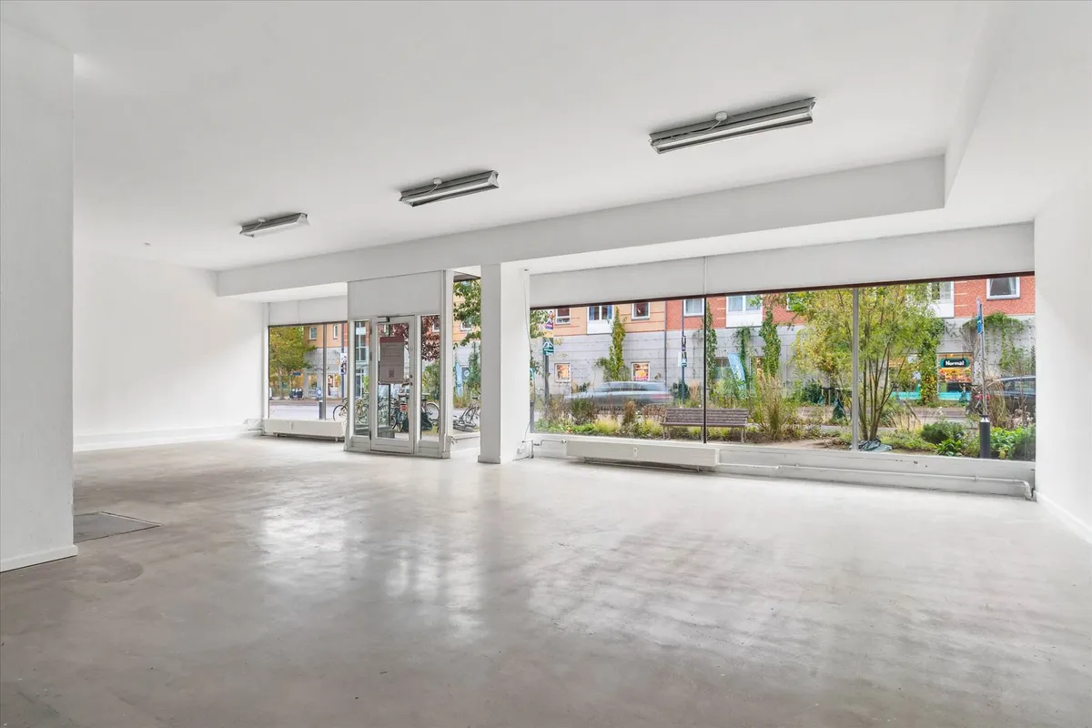 Velindrettet og ren butik med højt til loftet, lyse vinduer og møbler, gulv og vægge i hvidt og lysegråt