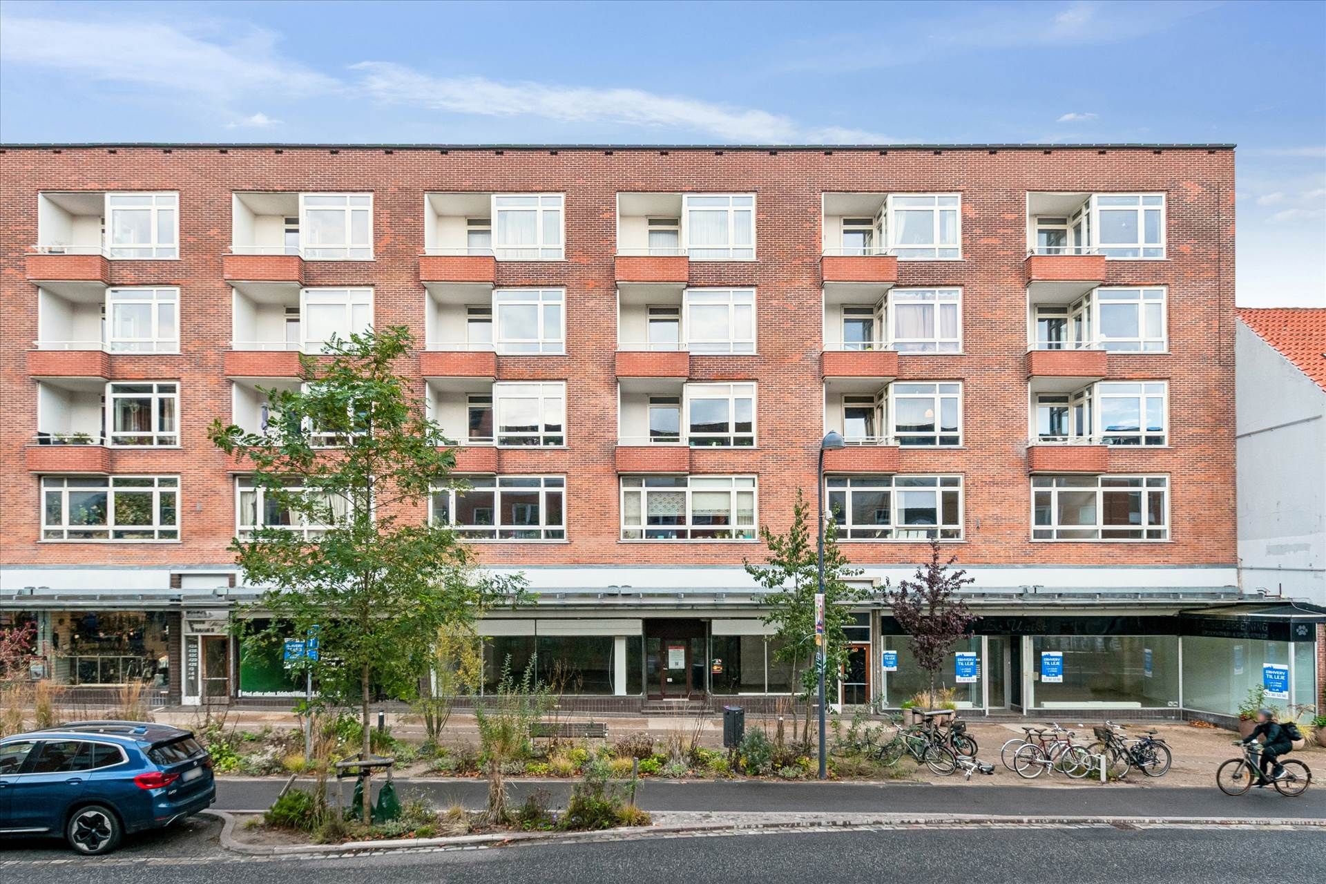 Butikslokaler med hele 12 meters facade, smukke høje lofter, parkerede cykler og en person cykler forbi