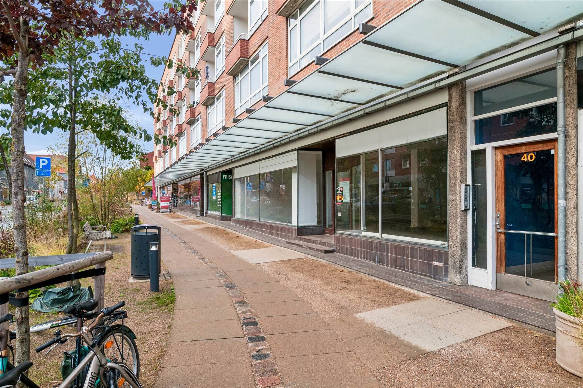 Butik med 12 meters facade. Parkeringsmuligheder og cykelstativ. Større forretning med store vinduer. Forretning med navnet