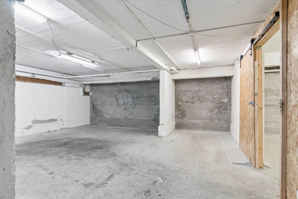 En stor og nyrenoveret kælder med to store parkeringspladser, hvor gulvet er hvidt og væggene er cement og hvidt