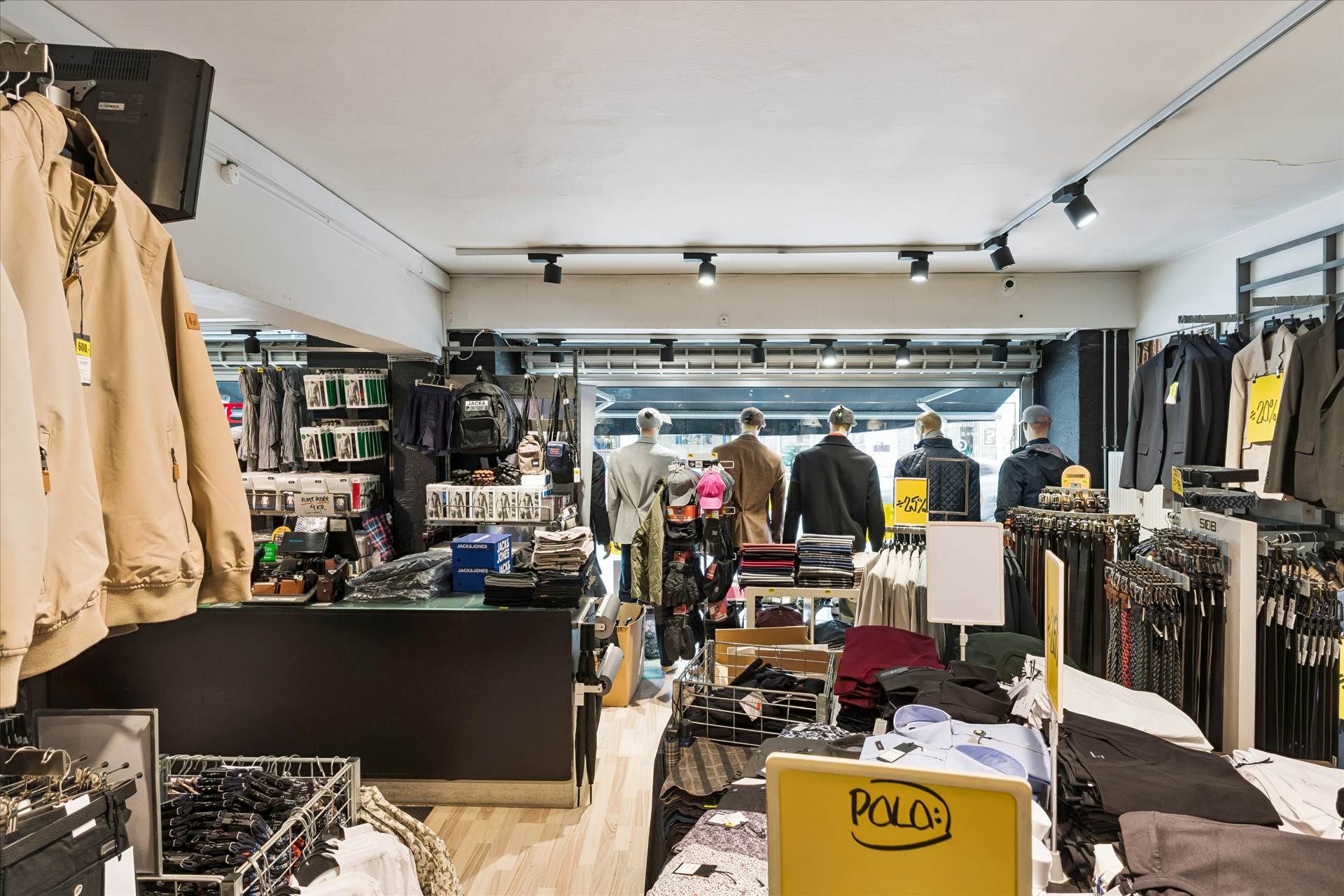 Butik med mange klæder og jakker i salg, sammen med skuffer og hylder med varer