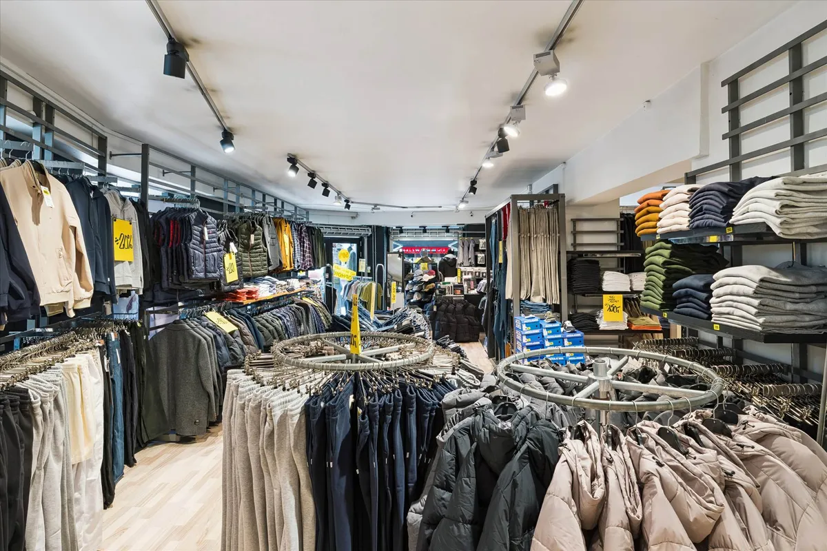 Lejet butik med klædeskab med tøj som jakker, bukser og trøjer, samt oplysninger om rabatter og salg i butikken