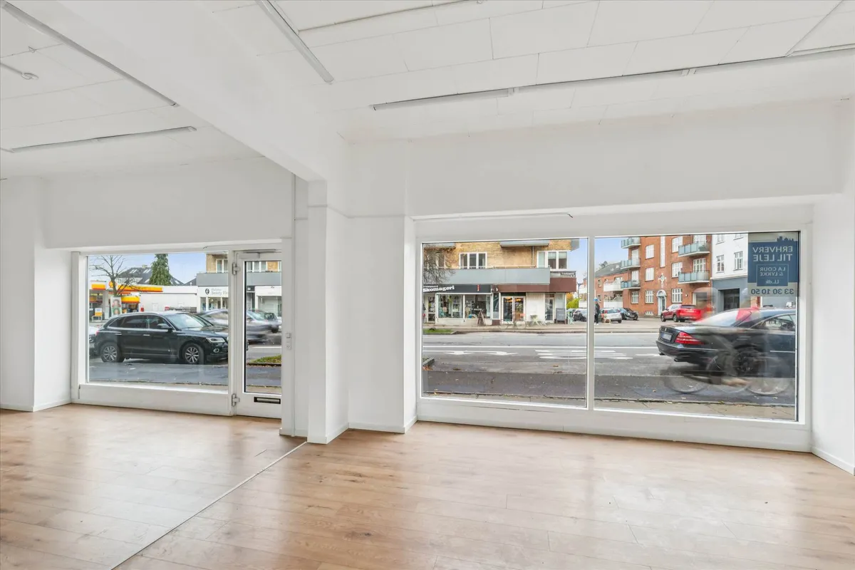 Butik med glasdøre og glasruder i hjertet af Brønshøj med udsigt til biler og bygninger