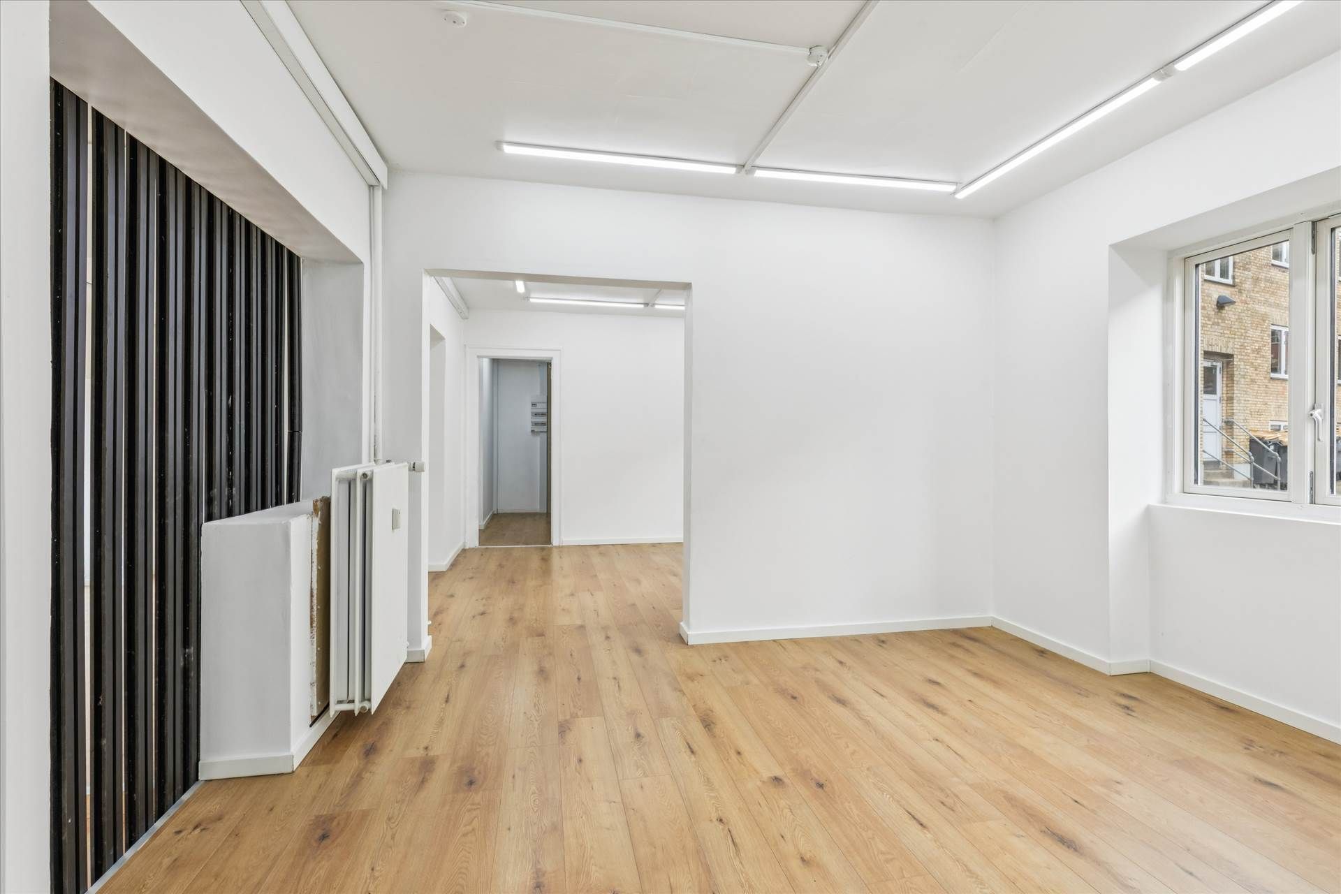 En tom butik med højt loft og lysegult lys, der skinner igennem store vinduer og vinduesruder i gulvet