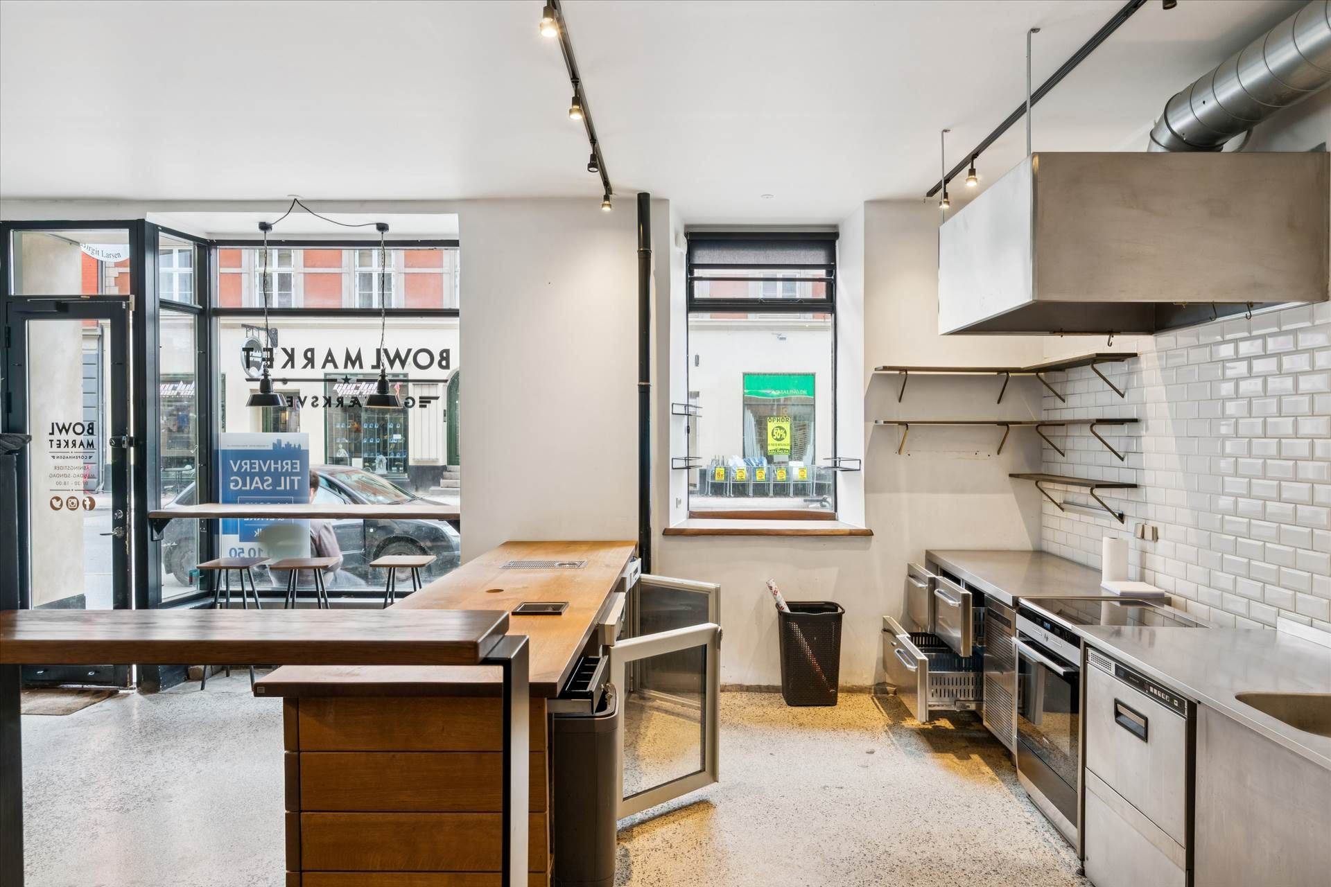 En moderne køkkeninteriør med rustfrit stålapparater, et drejebord, og lysekroner, der hænger fra loftet