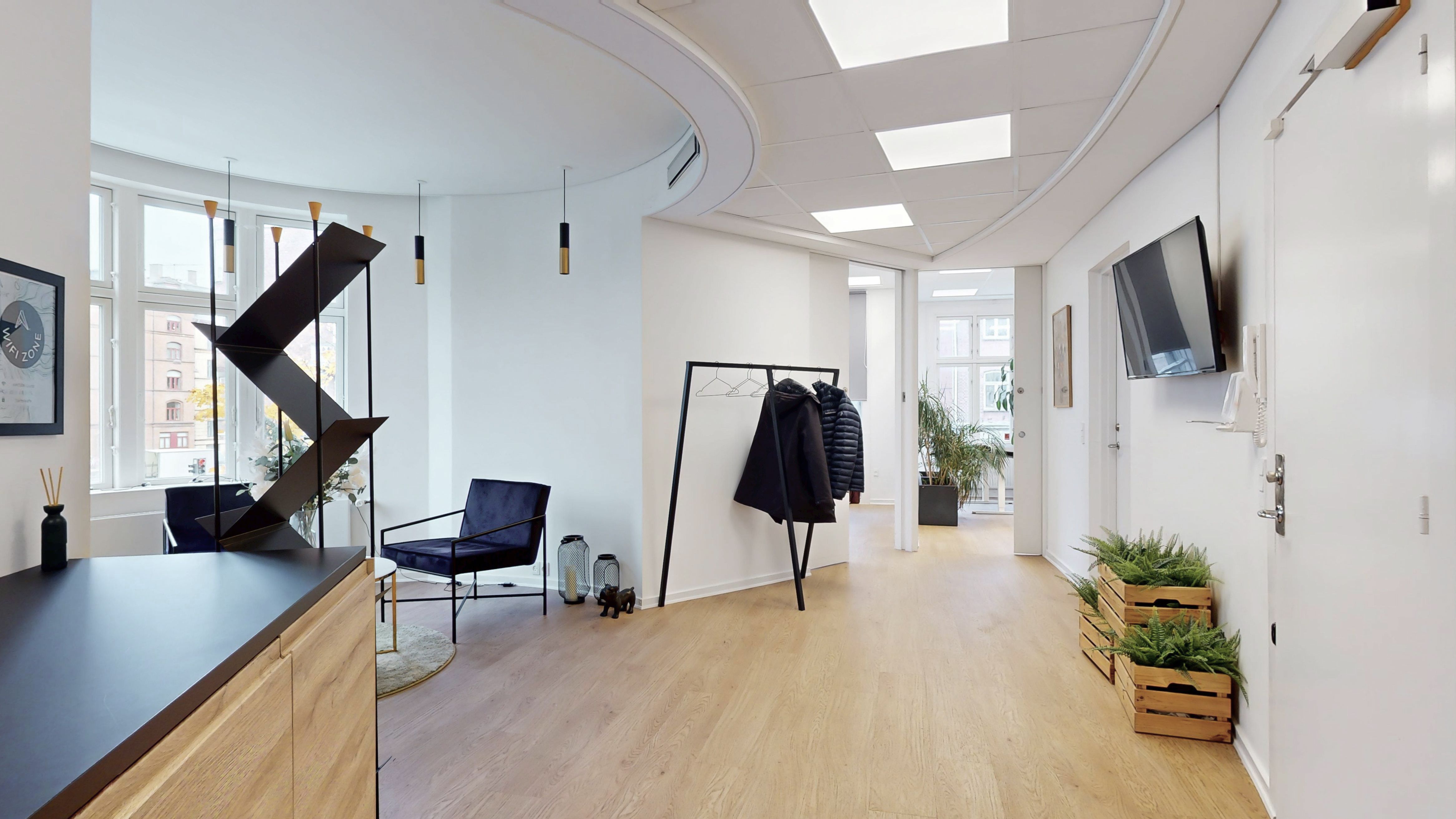 Elegant stue med moderne møbler og lyse loftslampe. Sort lænestol og lyse gulve med plante i trækasser