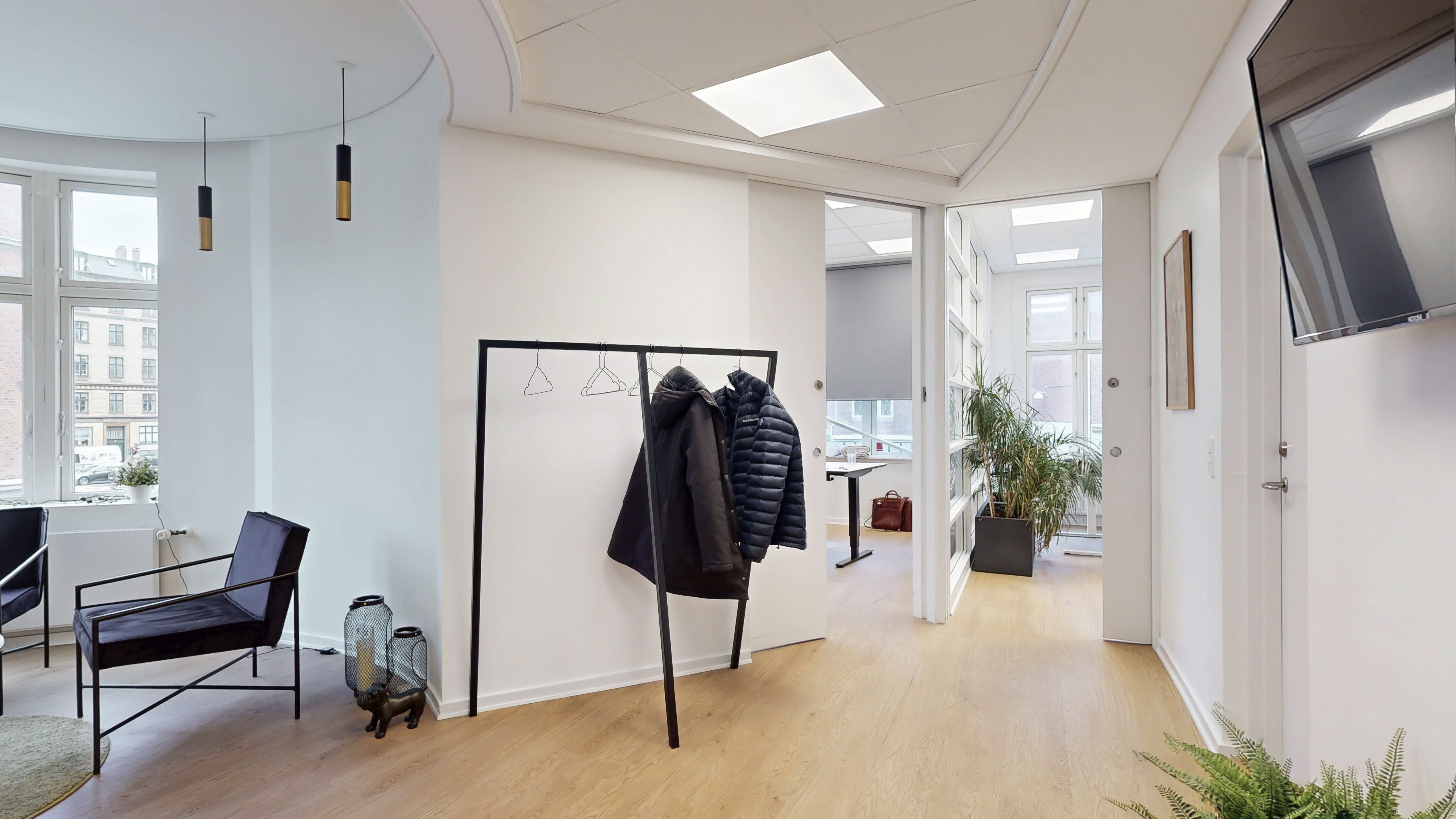 Lejlighed med moderne interiør og møbler, lyse og åbne områder, masser af planteliv og en hængelampe med to lyspærer