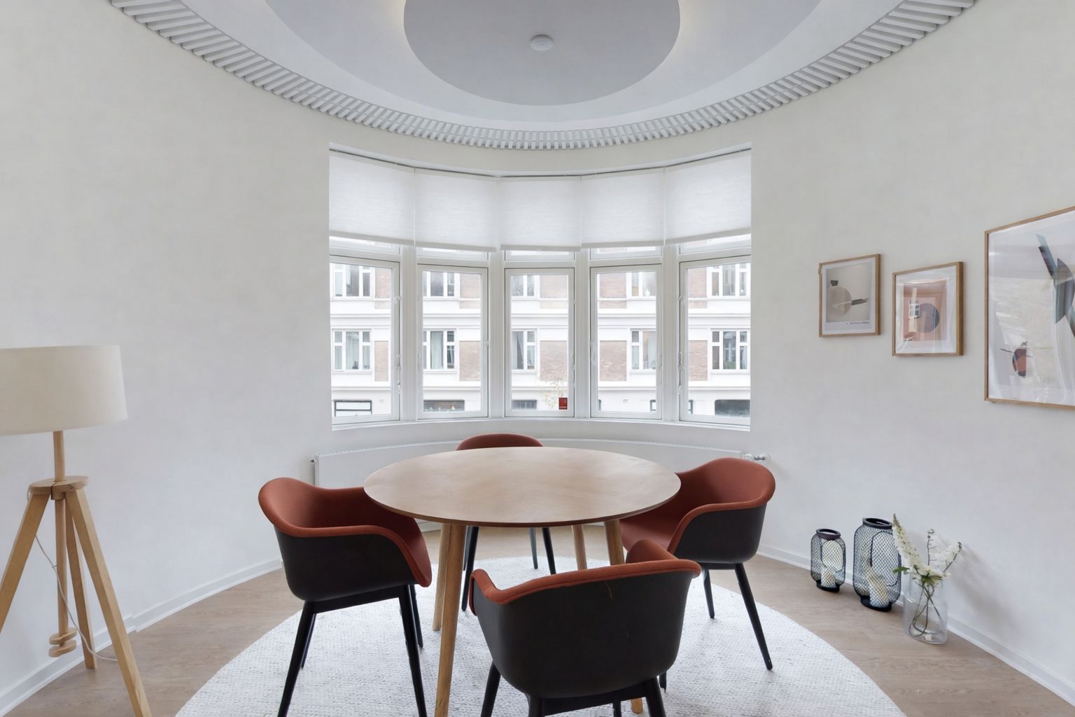 Velkommen til dette lyse erhvervslejemål med rundt bord og moderne møbler samt en hvid væg med malerier og vinduerne med udsigt til byen