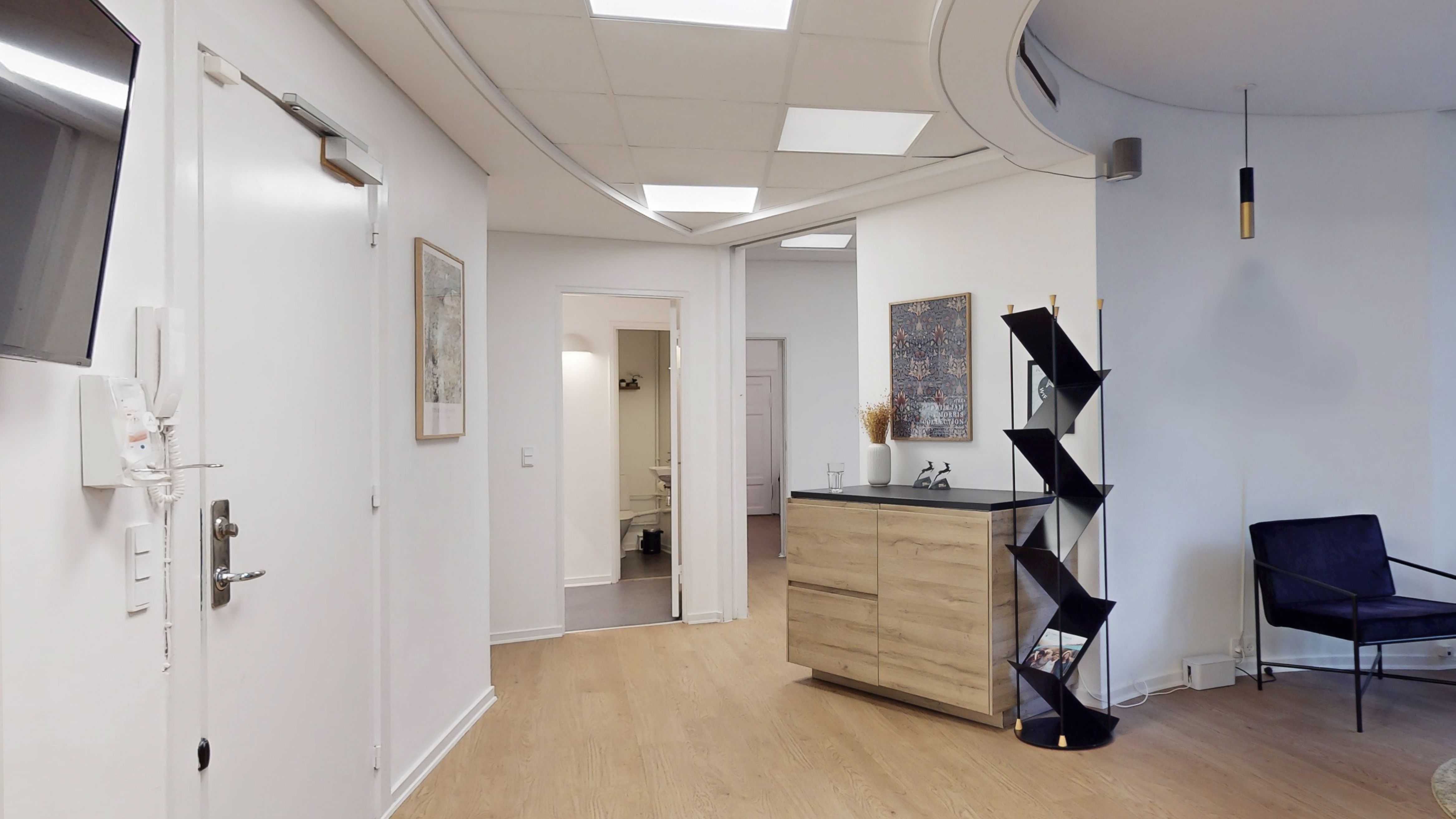 Lejlighed med højloft, moderne møbler og pæne dekorationer, hvidt gulv og lyse loftslampe. Toilet og opbevaringsskab i et