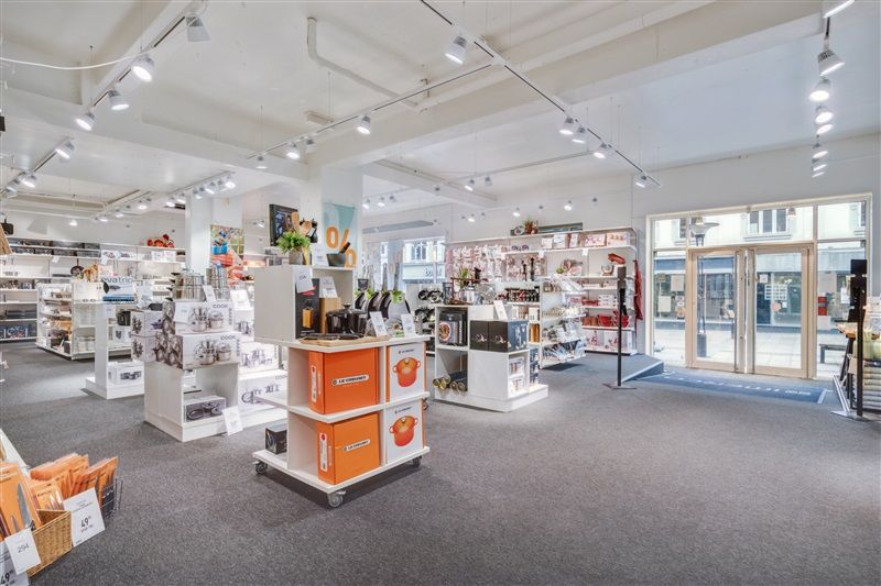 Butik med lyse loftslampe, stående hylder og tavle med skrift og illustrationer. Alle hylder med produkter og emballage i