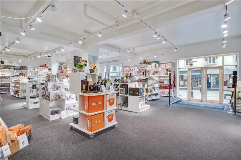 Butik med lyse loftslampe, stående hylder og tavle med skrift og illustrationer. Alle hylder med produkter og emballage i