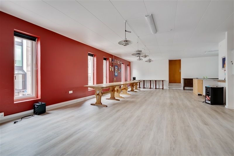 Store mødelokaler med lyse lofter og højt til loftet hængende loftlamper sammen med lysegult gulv og røde vægge