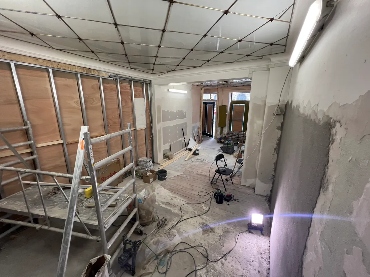 Forarbejde til ny butik med ny gulvbelægning, tømmervægge og højtloftet indretning i et renoveret lokale