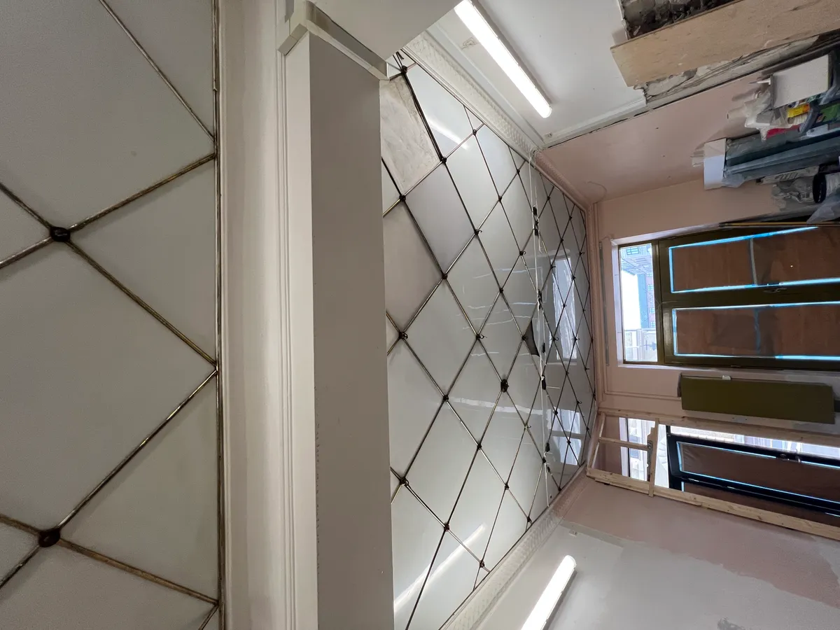 Foto af nyt interiør i butik med hvidt glas og mønstret vægpanel samt møbler og vinduer under renovering