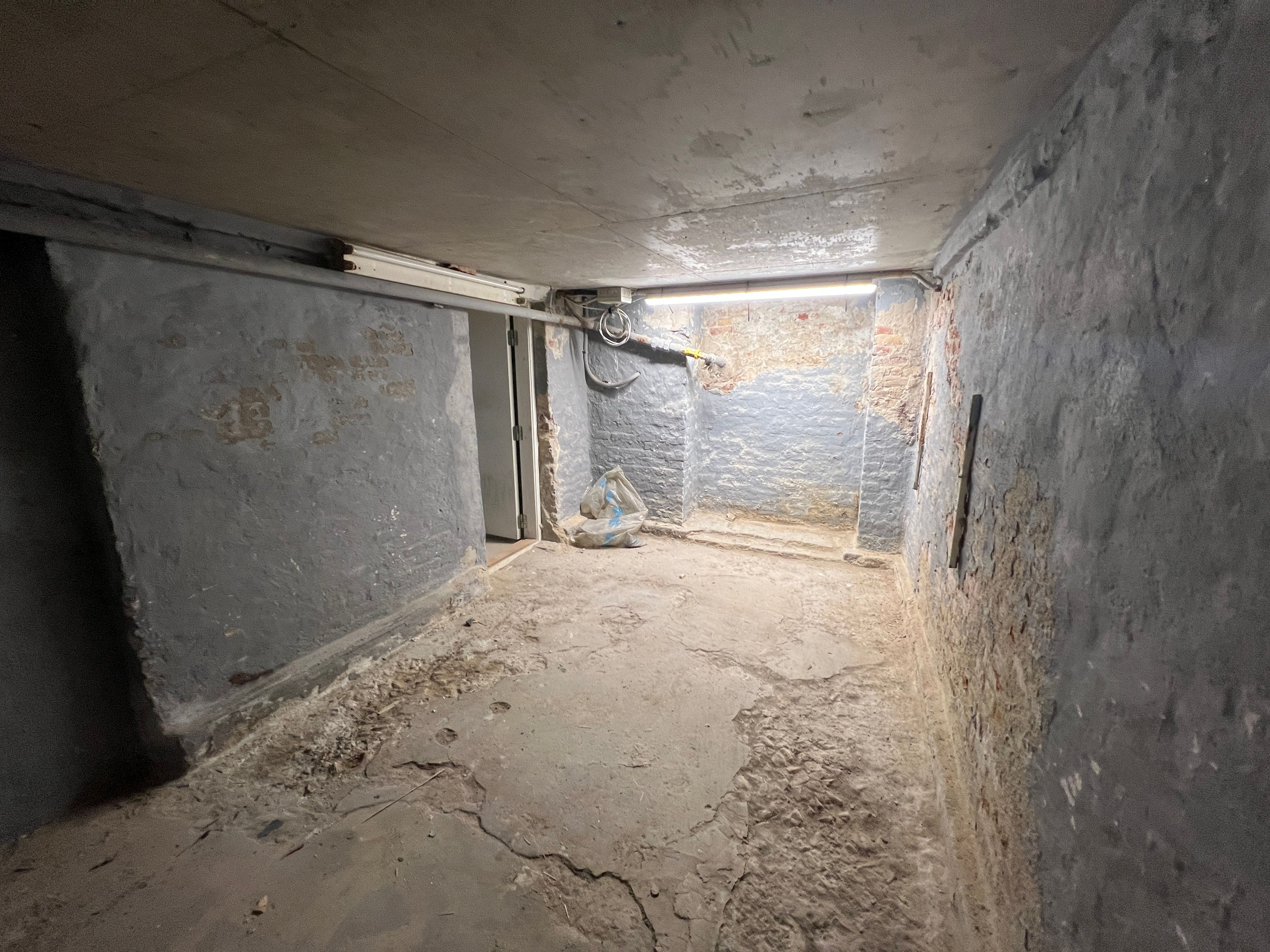 Nederdæk i mørke rum med lyse linjer, hvor der er en åbning og en rullegardin i enden af gangen