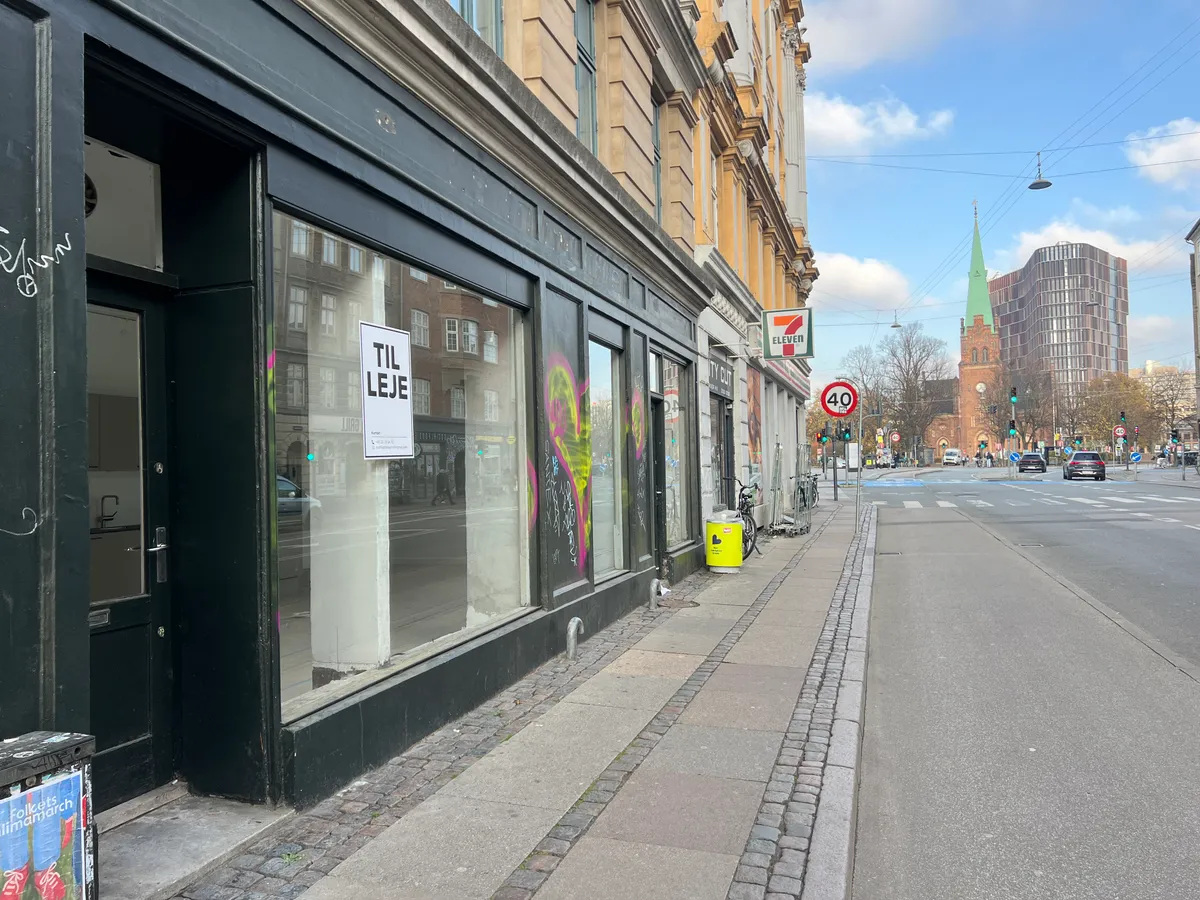Butikslejemål på Fælledvej med graffiti og skrifttegn på vinduet samt 40 km/t skilt og 7-Eleven-skilt