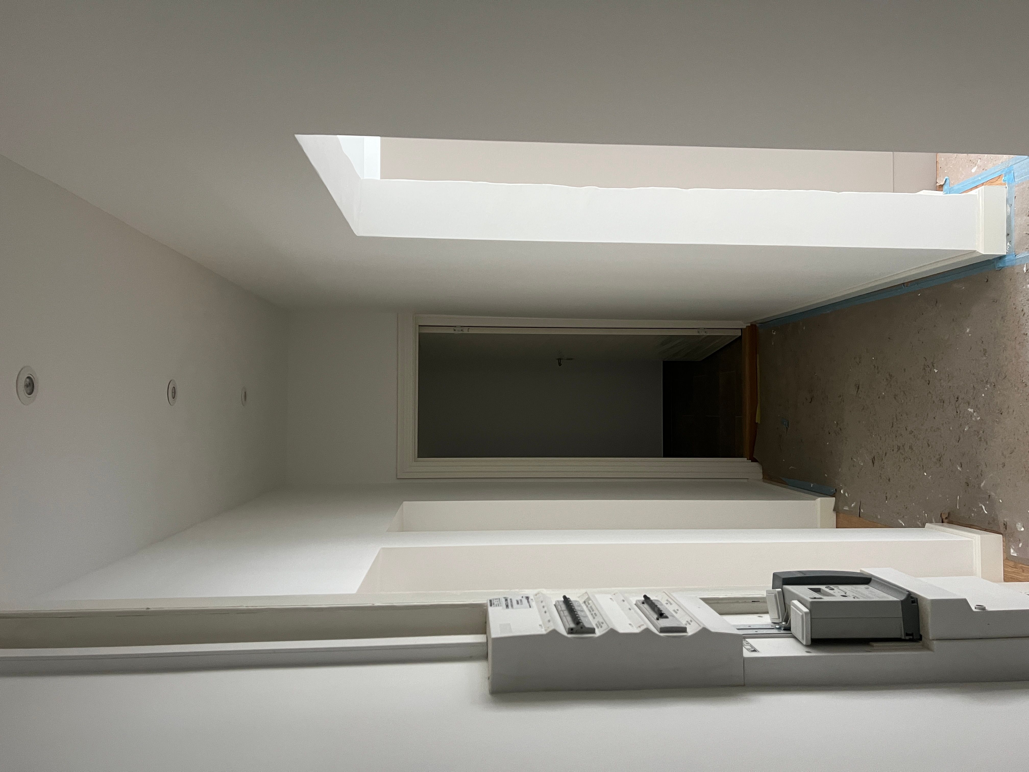 Hvid gulv med et print på højre side, højt til loftet med lyse og hvide vægge og loftsvinduer