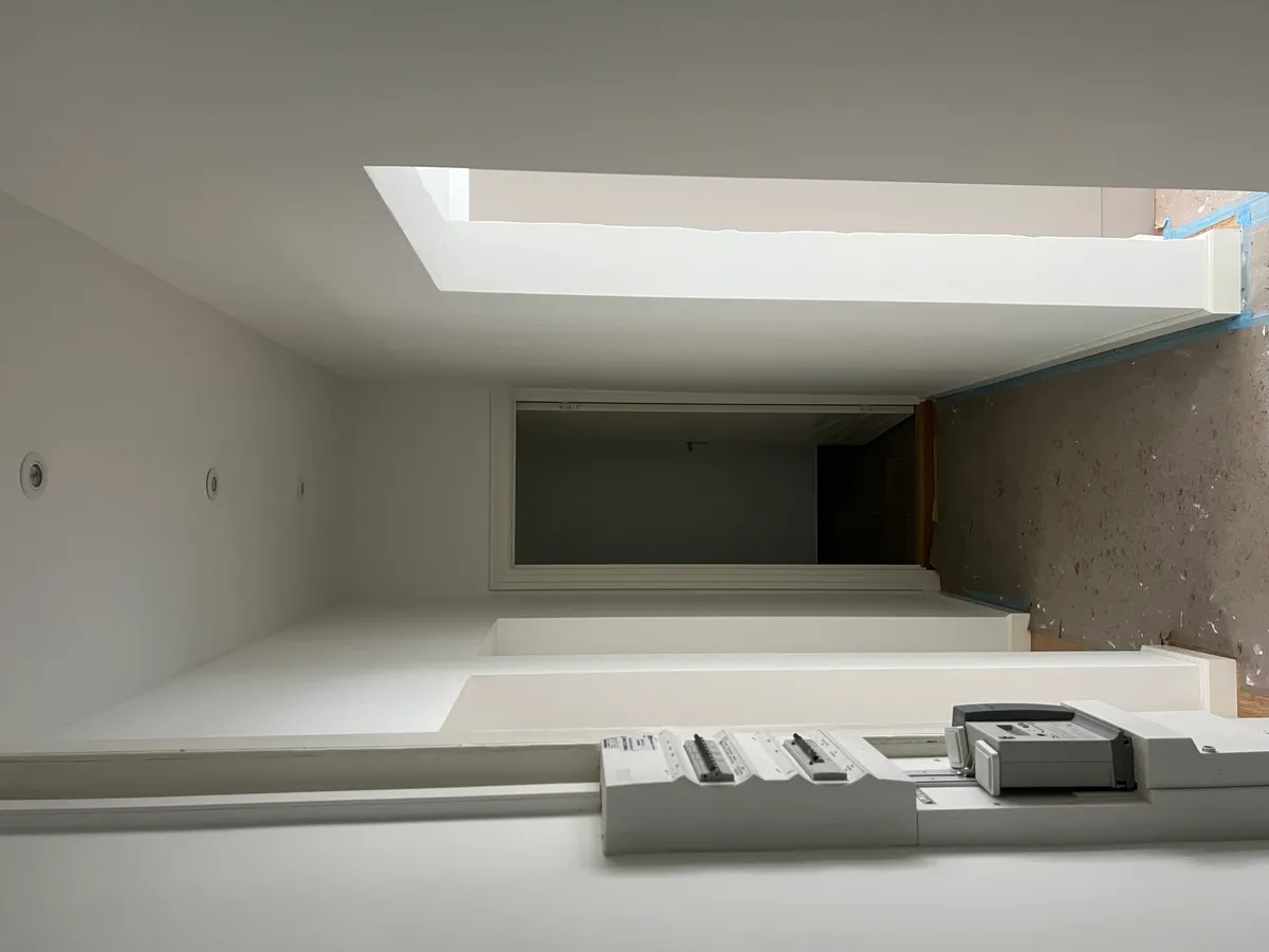 Hvid gulv med et print på højre side, højt til loftet med lyse og hvide vægge og loftsvinduer