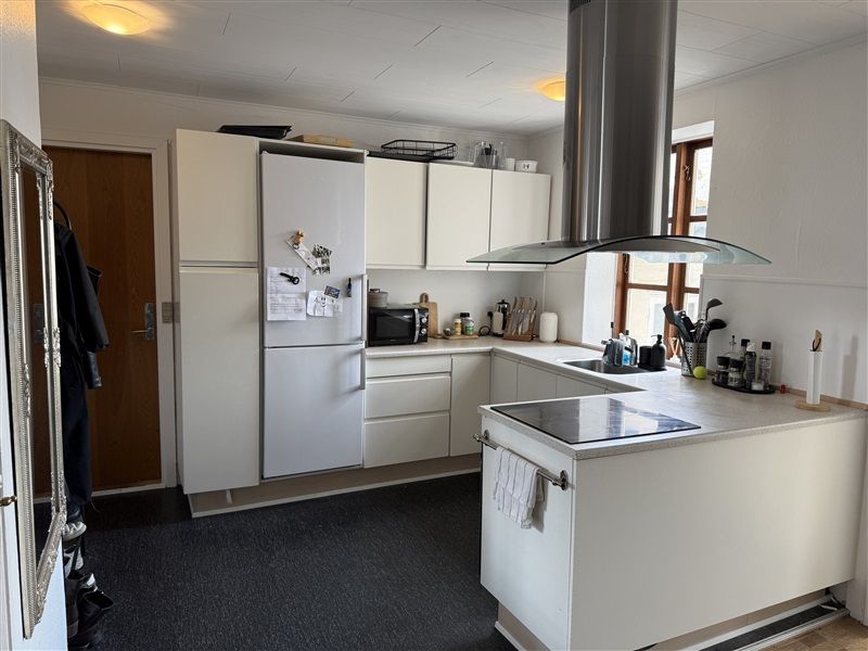 En velholdt og præsentable køkken med hvide møbler og en stor køleskab med magneter og noter samt en moderne ovn med en