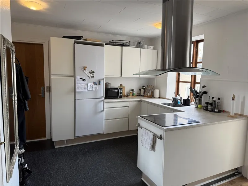 En velholdt og præsentable køkken med hvide møbler og en stor køleskab med magneter og noter samt en moderne ovn med en