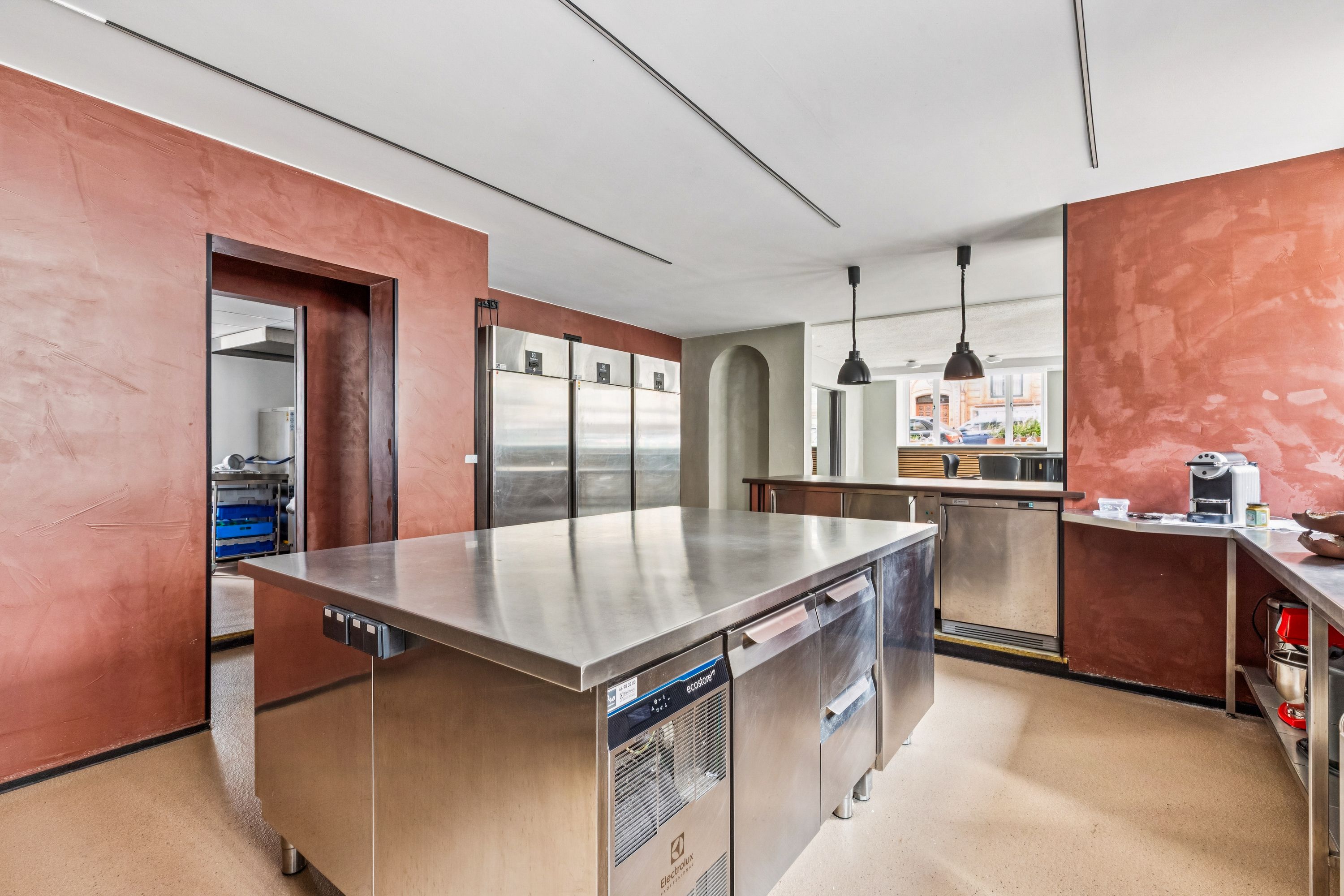 Moderne kommercielt køkken med rustfri stål arbejdsborde og skarpe røde vægge i Frederiksberg