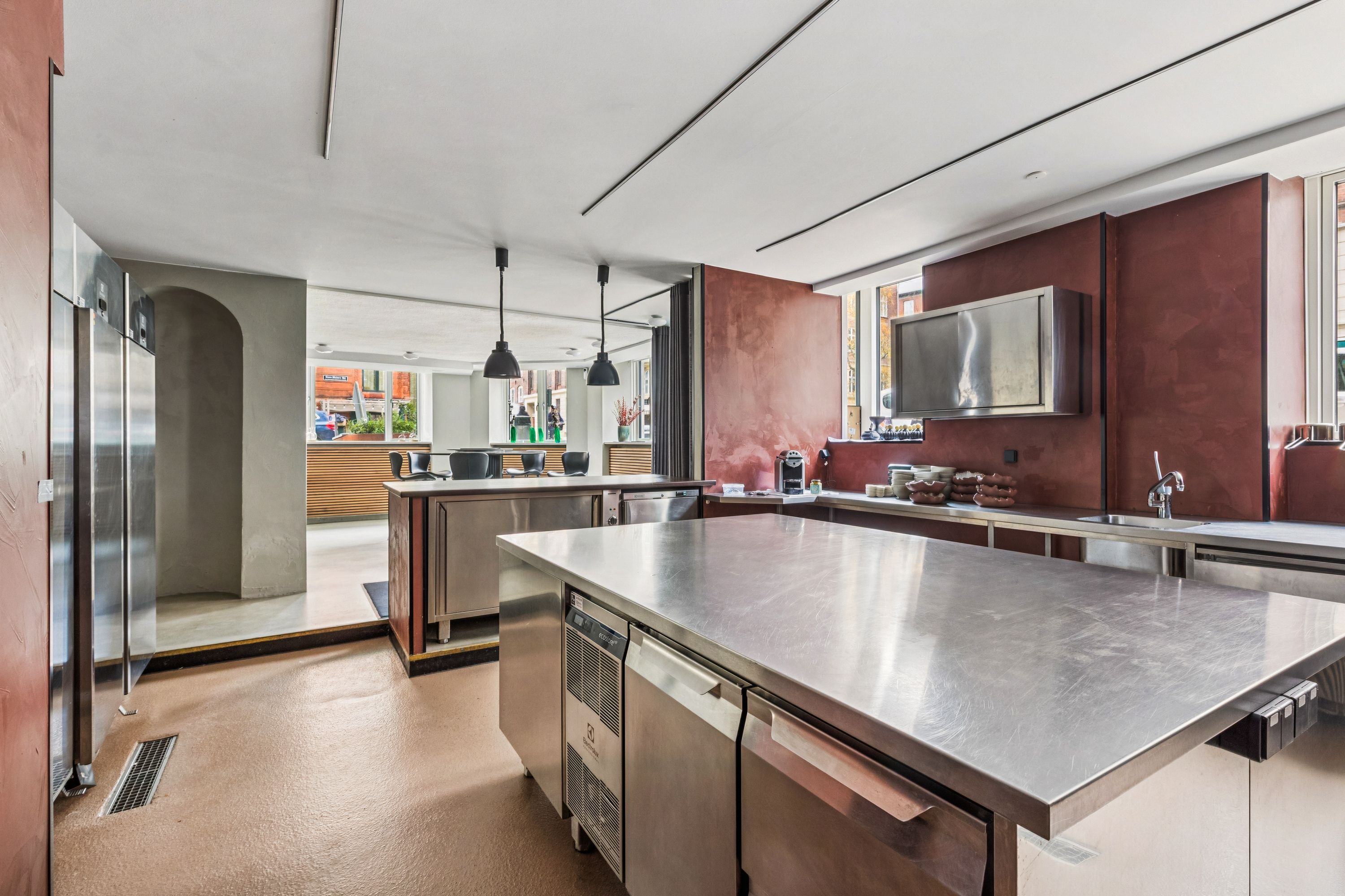 Lejlighed med køkken og moderne interiør på Smallegade 37B i Frederiksberg, med store metalkøkkenborde og lyserøde vægge