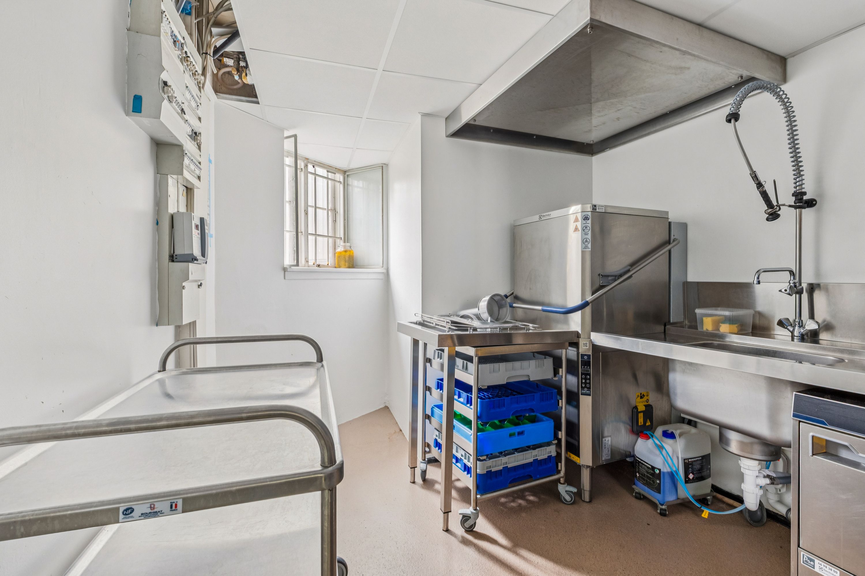 Alt om kommercielt køkken med renseri og skraldkasse. Moderne køkken med køleskab, vask, vaskemaskine og køkkenudstyr.